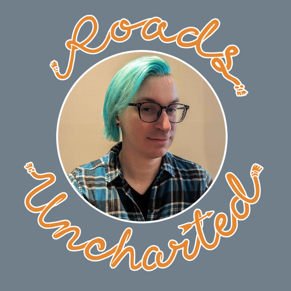 A headshot of Wren. A White masc-presenting person with teal colored hair, brown glasses, earrings and a septum piercing smiles at the camera. They wear a blue flannel shirt. Image is framed in a white circle with orange "Roads Uncharted" surrounding it.
